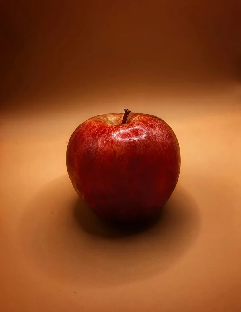 A glass jug of apple cider vinegar beside whole and halved apples